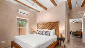 A bedroom with a wooden bed frame, a large window, and a view of the dining area. - Studio Near Santa Fe Farmers Market (Santa Fe)
