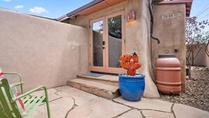 A house with a stone patio, a green chair, a blue pot with a cactus, and a large water tank. - Studio Near Santa Fe Farmers Market (Santa Fe)