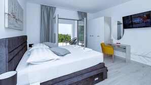Un dormitorio moderno con cama, escritorio, silla y televisor.