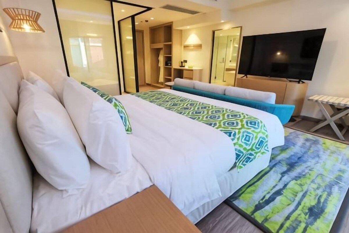 Una habitación de hotel con cama, televisión, escritorio y silla.