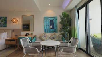 Una habitación de hotel moderna con una cama, una mesa de comedor con sillas, un sofá con cojines, un espejo grande y una planta en maceta.
