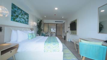 Una habitación de hotel moderna con una cama grande, un escritorio, una silla, un televisor y un baño visible al fondo.