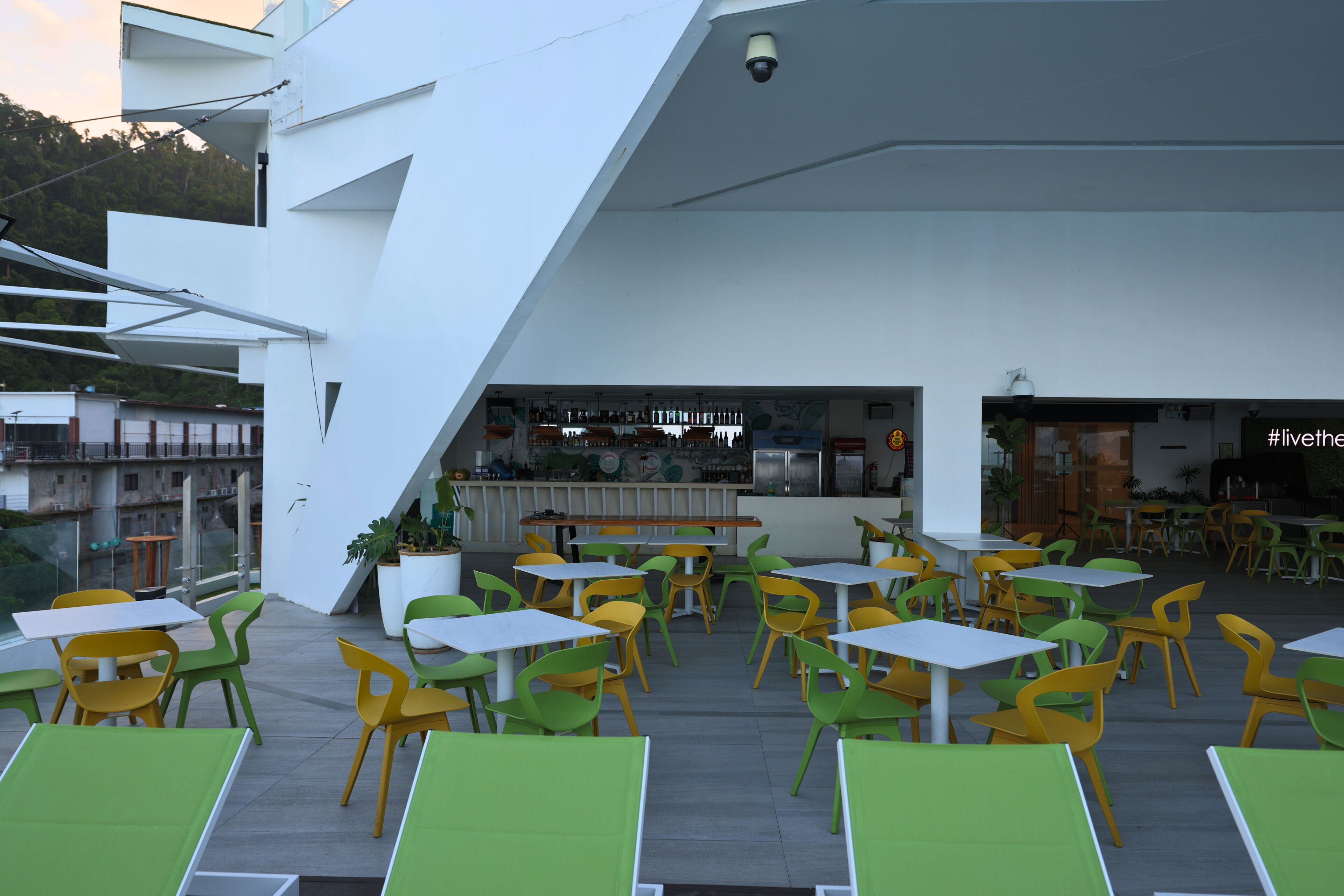A rooftop dining area with outdoor seating, a bar, and a view of the cityscape.