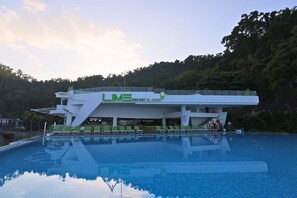 A modern resort building with a pool and lounge chairs. - Lime Resort El Nido (El Nido)