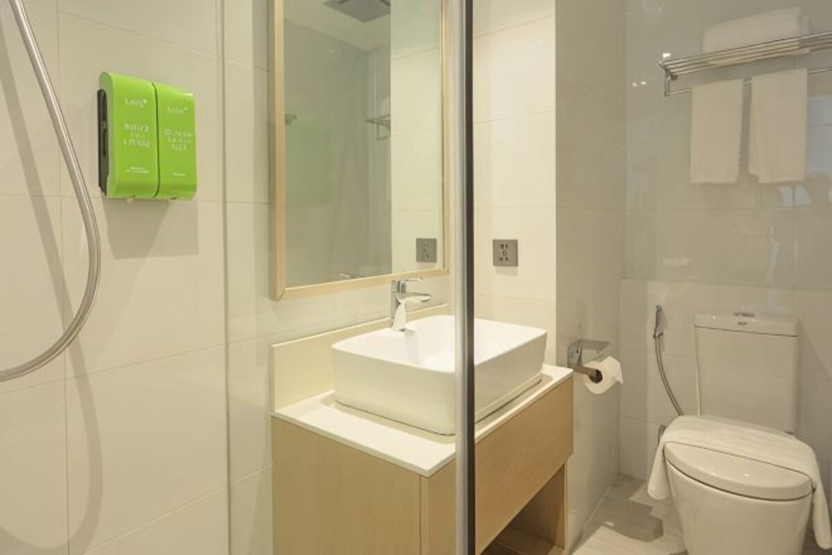 Un baño moderno con cabina de ducha de vidrio, un lavabo blanco y un inodoro.
