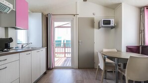 Eine kompakte Küche mit Mikrowelle, Kaffeemaschine und einer Schiebetür zum Balkon.