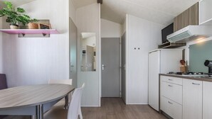 Eine moderne Küche mit Essbereich, ausgestattet mit einem Holztisch, weißen Stühlen und einem eingebauten Herd.