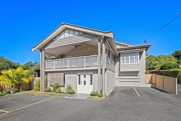 A two-story building with a balcony, a garage, and a covered parking area. - Urban Getaway Whole Home - 6BR/5BA, Sauna, Ipswich (Newtown)