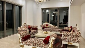 A room with a large glass door, a chandelier, and a sofa set with red cushions. - Entire Luxury 2BHK Flat for Parties/ Family (New Delhi)