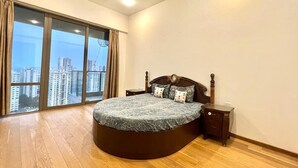 A bedroom with a large bed, a nightstand, and a window with a city view. - Entire Luxury 2BHK Flat for Parties/ Family (New Delhi)
