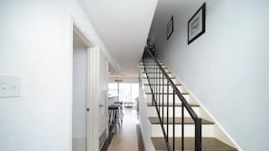 Una escalera con barandilla negra que lleva a un rellano.