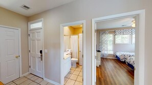 Ein Zimmer mit einem Bett, einem Fenster mit Vorhängen und einem Badezimmer mit Toilette und Waschbecken.