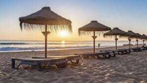 A beach with thatched umbrellas and lounge chairs. - Herdade dos Salgados, T3 8C-0C, Vila das Lagoas (Albufeira)