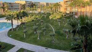 A resort with a swimming pool, neatly trimmed lawns, and palm trees. - Herdade dos Salgados, T3 8C-0C, Vila das Lagoas (Albufeira)