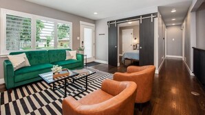 A modern living room with a green sofa, two leather armchairs, and a black and white striped rug.