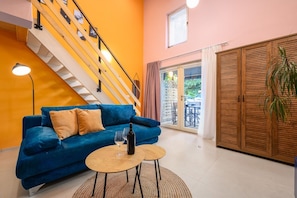 A modern living room with a blue sofa, a wooden staircase, and a large wooden wardrobe.