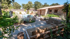 Un espace extérieur rustique comprenant un bâtiment en pierre, une terrasse en bois et une piscine.