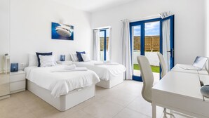A modern bedroom with two beds, a desk, and a laptop.