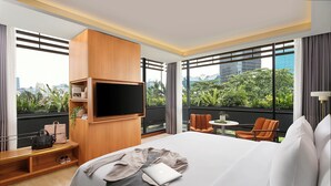 Quarto de hotel com cama grande, televisão fixada na parede, mesa pequena e uma cadeira.