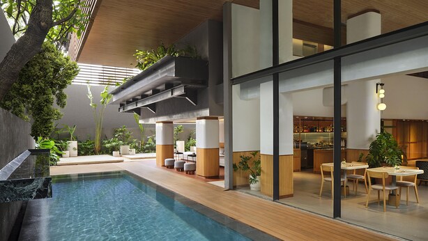 Área interna moderna de piscina com água cristalina, deck de madeira e espaços de estar.