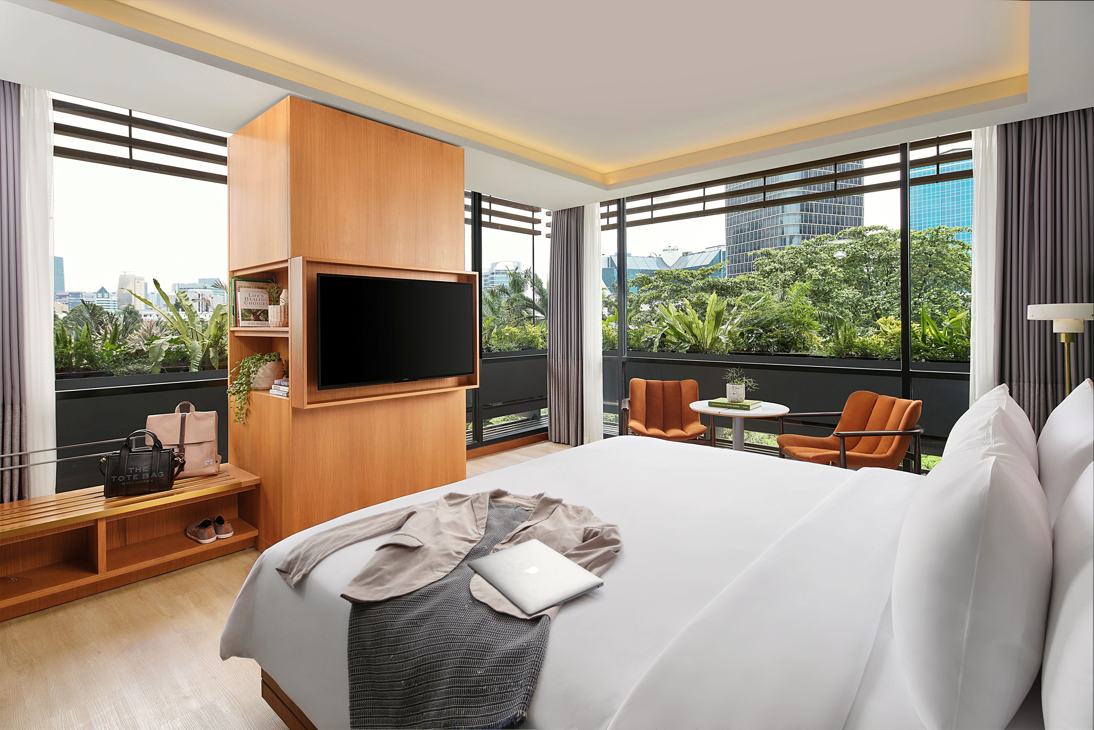 Habitación de hotel con una cama grande, un televisor montado en la pared, una mesita y una silla.