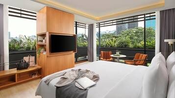 Habitación de hotel con una cama grande, un televisor montado en la pared, una mesita y una silla.