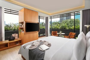 A hotel room with a large bed, a TV mounted on the wall, a small table, and a chair.