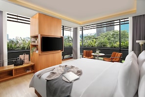 A hotel room with a large bed, a TV mounted on the wall, a small table, and a chair.
