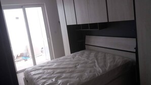 Et soveværelse med en seng, en skydedør til en balkon og indbyggede skabe.