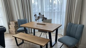 Uma sala de estar moderna com uma mesa de jantar de madeira, duas cadeiras azuis, um banco e uma planta decorativa.