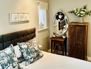 Ein Schlafzimmer mit Bett, Kommode, Spiegel und Fenster.