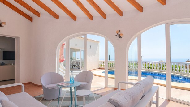 Ein geräumiger Balkon mit Pool, heller Möbel und Meerblick.