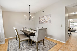 A dining area with a wooden table, grey upholstered chairs, and a chandelier.