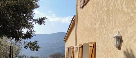 Une terrasse extérieure avec une table et des chaises, un mur en pierre et une vue sur les montagnes.