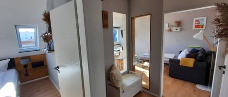 A modern interior with a wooden floor, a sofa, a desk, and a chair.