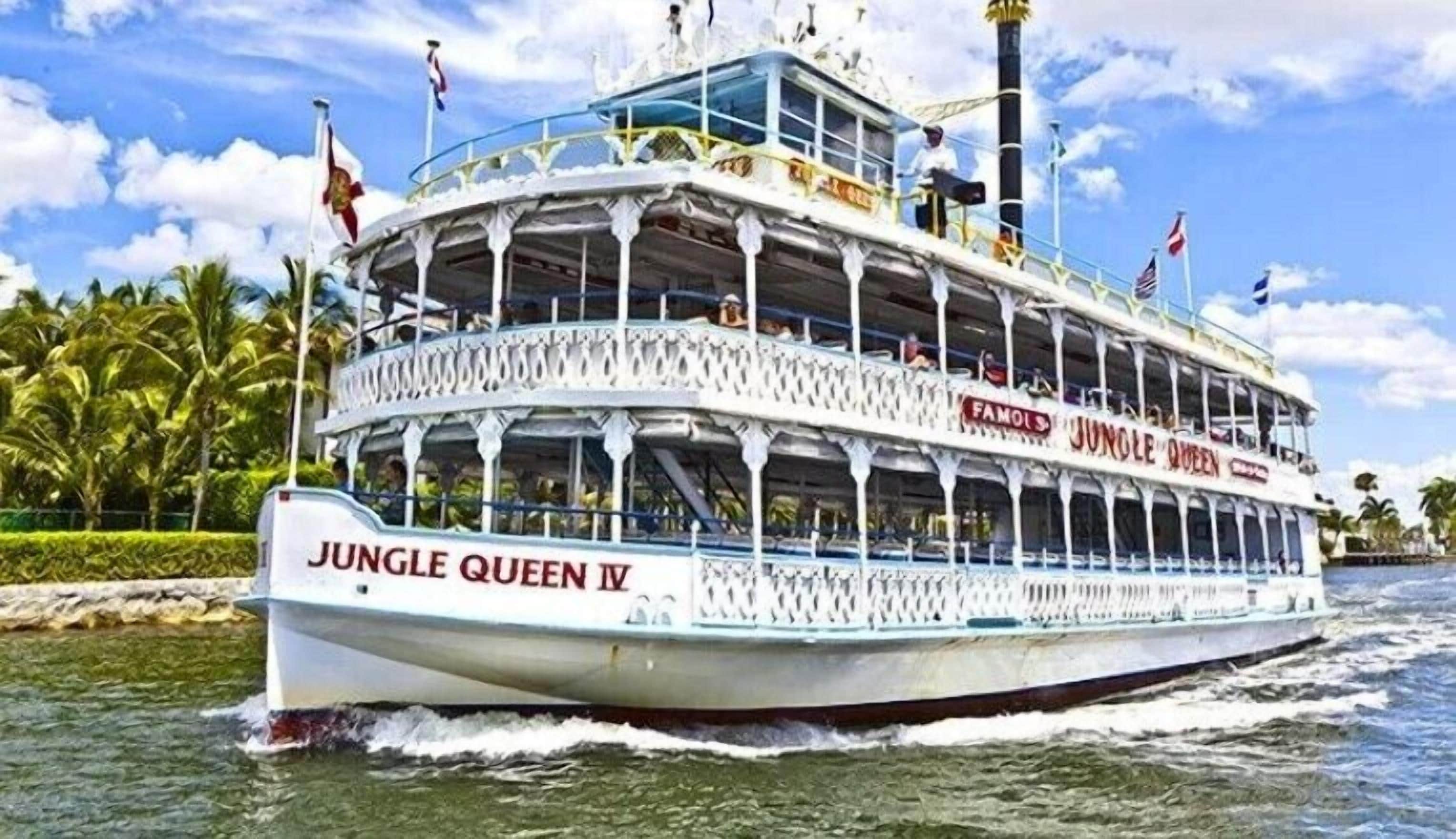 A double-decked river cruise ship named 'Jungle Queen IV' with multiple decks and passengers visible.