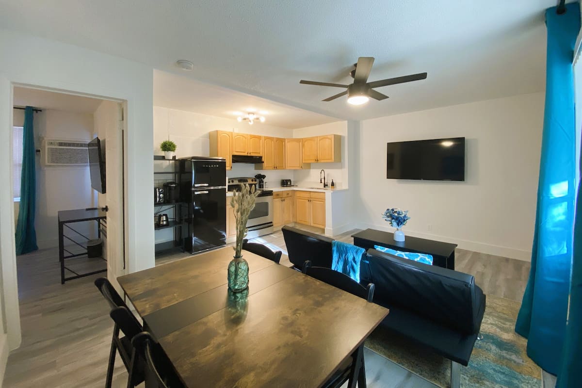 A modern kitchen with wooden cabinets, a black refrigerator, and a ceiling fan.