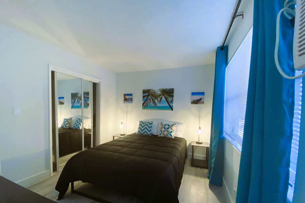 A bedroom with a bed, bedside tables, a mirror, and wall art.