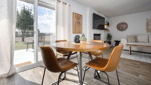 Uma sala de jantar moderna com uma mesa redonda e cadeiras de couro, uma lareira e uma televisão grande na parede.