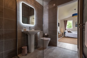 A modern bathroom with a large mirror, sink, and toilet.