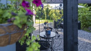 A covered outdoor seating area with a table and chairs, surrounded by gravel and greenery. - Newly Renovated, Stylish Self-catering Apartment (Dawros)