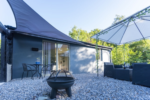 A modern outdoor seating area with a fire pit, a table with chairs, and a covered patio.