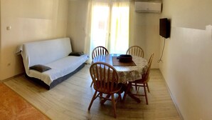 Una habitación con sofá, mesa de comedor, sillas y televisor.