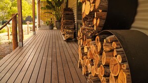 A wooden deck with a covered area, surrounded by a wooden fence and potted plants. - Blackwood Bush Retreat (Strathewen)