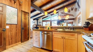 A kitchen with wooden cabinets, stainless steel appliances, and pendant lighting.