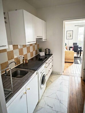 A compact kitchen with a sink, stove, and a built-in washing machine.