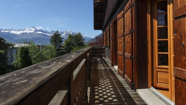 Ein Holzbalkon mit Blick auf schneebedeckte Berge.