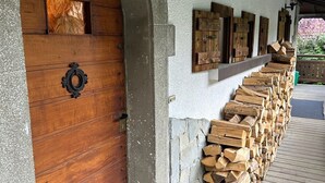 Eine Holztür mit Metallgriff, eine Steinsäule und eine Holztreppe, die zu einer Veranda führt.