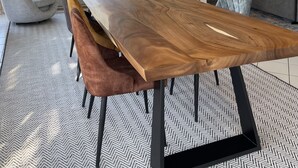 Ein geräumiger Essbereich mit einem langen Holztisch, modernen Stühlen und einem Deckenventilator.