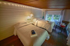Two single beds with white duvets, a small table, and a chair create a comfortable space.
